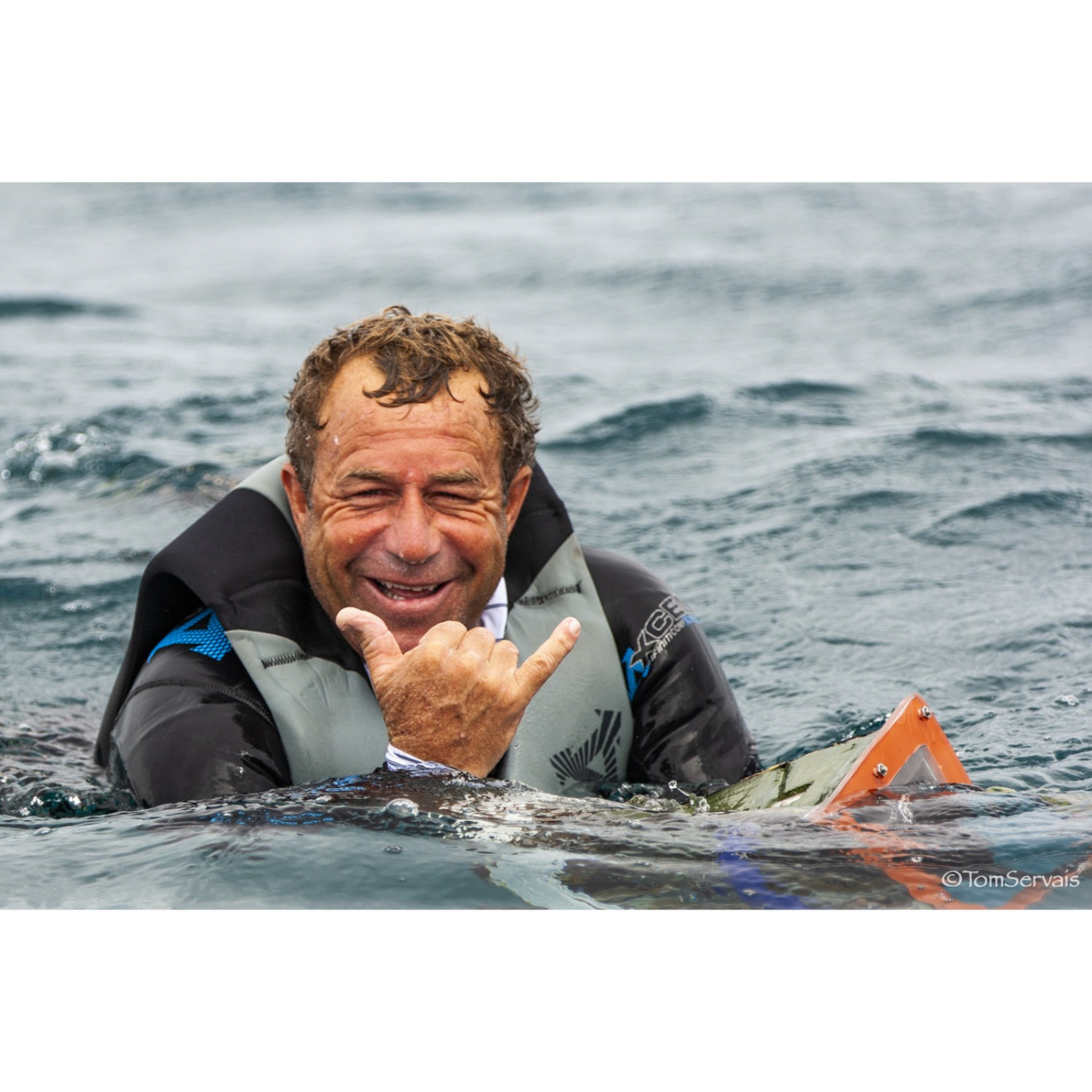 Larry Haynes in the water throwing a shaka